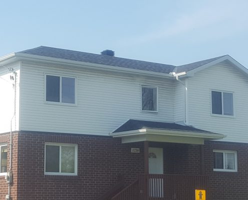 two tone building with vinyl and brick siding, lots of windows and 1 door with handicap ramp